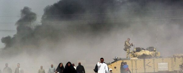 Um grupo de iraquianos fogem de Basra, sul do Iraque, passando perto de um tanque britânico, em 29 de março de 2003 - Sputnik Brasil