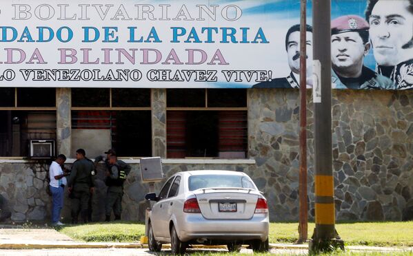 Membros das forças de segurança sob retratos do presidente da Venezuela, Nicolás Maduro, do ex-presidente Hugo Chávez e do herói nacional da Venezuela, Simon Bolivar, fora da base militar da Brigada Blindada Fuerte Paramacay, em Valência, Venezuela, em 6 de agosto de 2017. - Sputnik Brasil