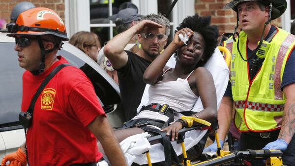 Rescue personnel help an injured woman after a car ran into a large group of protesters after an white nationalist rally in Charlottesville, Va., Saturday, Aug. 12, 2017. - Sputnik Brasil