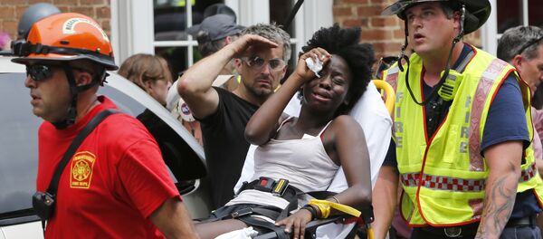 Rescue personnel help an injured woman after a car ran into a large group of protesters after an white nationalist rally in Charlottesville, Va., Saturday, Aug. 12, 2017. - Sputnik Brasil