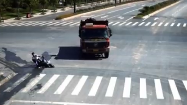 O homem caiu de sua motocicleta elétrica na estrada da província de Zhejiang (China). Por pouco não entrou nas rodas deste caminhão. - Sputnik Brasil