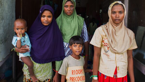 In this photograph taken on May 28, 2015, Rohingya migrant women from Myanmar (L-R) Rubuza Hatu, 21, Rehana Begom, 24 and Rozama Hatu, 23, stand at a confinement camp at Bayeun district in Indonesia's Aceh province after Indonesian fishermen rescued about 400 Rohingya migrants from Myanmar and Bangladesh from a boat on May 20, 2015 off the eastern coast of Aceh. - Sputnik Brasil