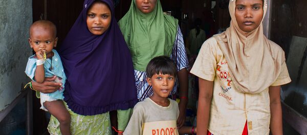 In this photograph taken on May 28, 2015, Rohingya migrant women from Myanmar (L-R) Rubuza Hatu, 21, Rehana Begom, 24 and Rozama Hatu, 23, stand at a confinement camp at Bayeun district in Indonesia's Aceh province after Indonesian fishermen rescued about 400 Rohingya migrants from Myanmar and Bangladesh from a boat on May 20, 2015 off the eastern coast of Aceh. - Sputnik Brasil