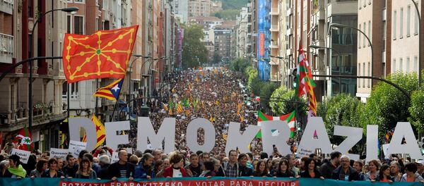 Milhares de manifestantes caminham atrás de uma bandeira em que se lê Votar para decidir Democracia, Catalunha, estamos com você, durante uma marcha organizada pela organização de independência pro-basca. - Sputnik Brasil