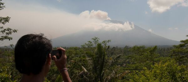 A local resident takes a picture of Mount Agung, an active volcano that authorities say is showing increased activity, from a monitoring station in Rendang Village, Karangasem on the resort island of Bali, Indonesia September 19, 2017 - Sputnik Brasil