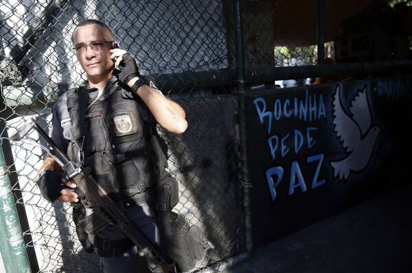 Policial militar ao lado de mensagem de paz na comunidade da Rocinha, no Rio de Janeiro (RJ) - Sputnik Brasil