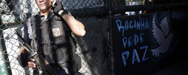 Policial militar ao lado de uma mensagem de paz na comunidade da Rocinha, no Rio de Janeiro - Sputnik Brasil