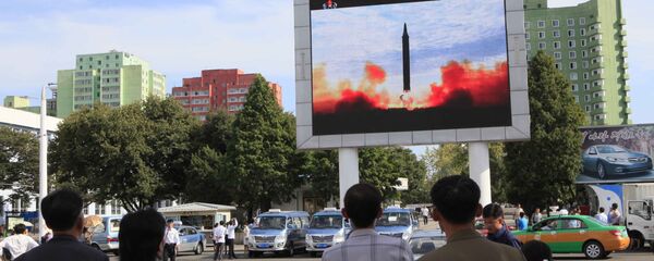 As pessoas a ver o lançamento do míssil balístico Hwasong-12 na televisão da estação ferroviária em Pyongyang, Coreia do Norte, 16 de setembro de 2017 - Sputnik Brasil