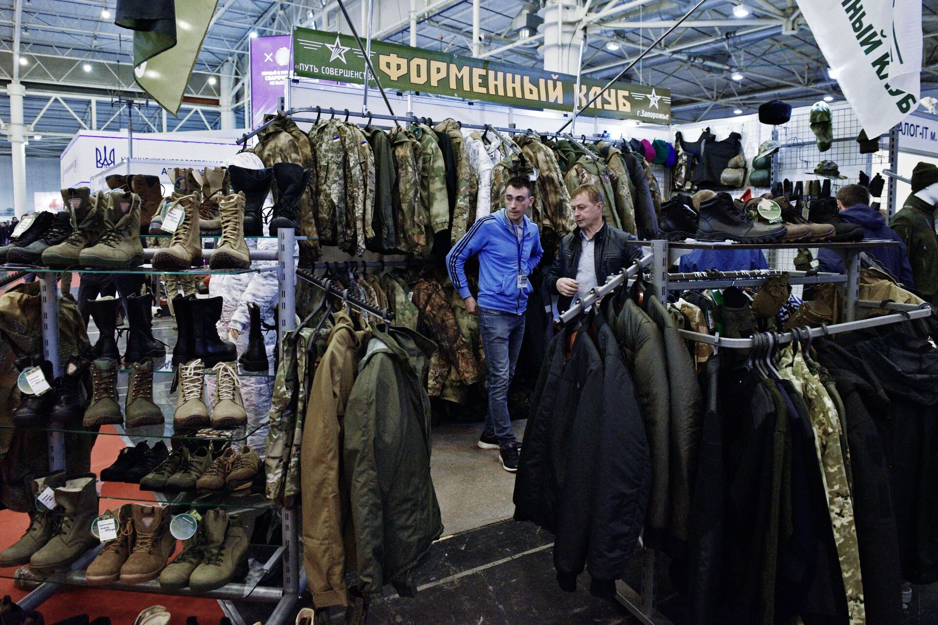 Homens examinam roupa, calçado e uniformes militares durante a exposição Armas e Segurança 2017 em Kiev - Sputnik Brasil, 1920, 06.12.2021