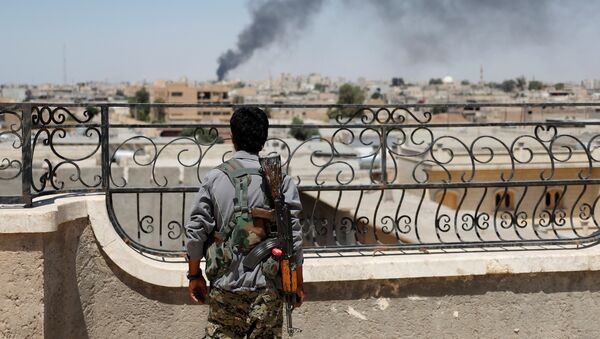 Soldado curdo olhando para fumaça depois de ataques aéreos da coalizão em Raqqa (foto de arquivo) - Sputnik Brasil