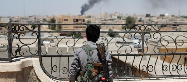 Soldado curdo olhando para fumaça depois de ataques aéreos da coalizão em Raqqa (foto de arquivo) - Sputnik Brasil