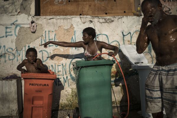Mulher e criança tomam banho em contentores para lixo na favela da Mangueira, Rio de Janeiro - Sputnik Brasil