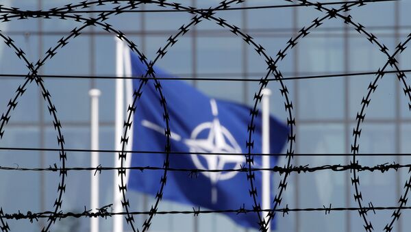 A bandeira da OTAN vista através de cerca farpada em frente à nova sede da OTAN em Bruxelas, maio de 2017 - Sputnik Brasil