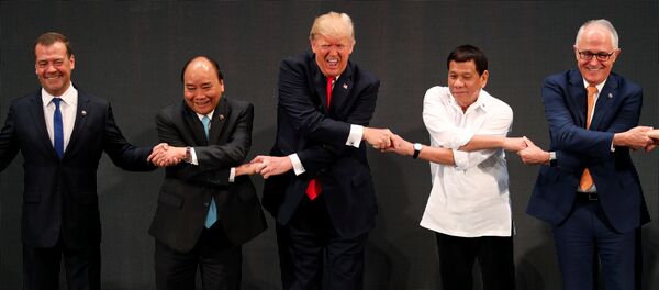 U.S. President Donald Trump smiles with other leaders, including Russia's Prime Minister Dmitry Medvedev, Vietnam's Prime Minister Nguyen Xuan Phuc, President of the Philippines Rodrigo Duterte and Australia's Prime Minister Malcolm Turnbull, as they cross their arms for the traditional ASEAN handshake in the opening ceremony of the ASEAN Summit in Manila, Philippines November 13, 2017 - Sputnik Brasil
