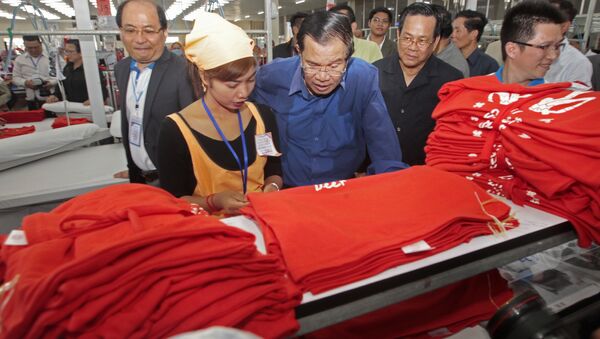 Cambodian Prime Minister Hun Sen, center, leans over a garment worker - Sputnik Brasil