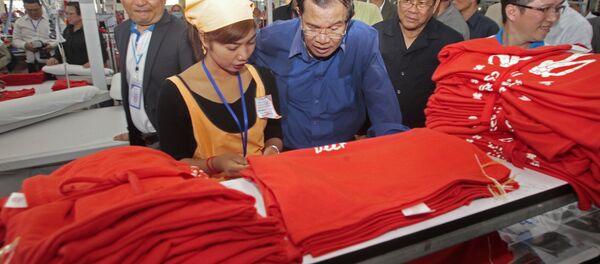 Cambodian Prime Minister Hun Sen, center, leans over a garment worker - Sputnik Brasil