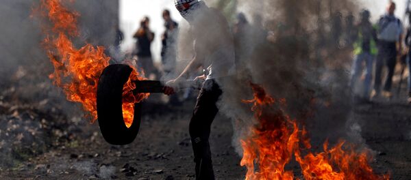 Palestino mascarado segurando um pneu em chamas durante confrontos com tropas israelenses em uma aldeia na Cisjordânia, 10 de novembro de 2017 - Sputnik Brasil