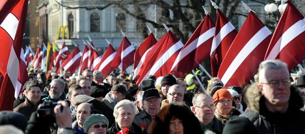 People carry Latvian flags at the march in Riga, Latvia - Sputnik Brasil