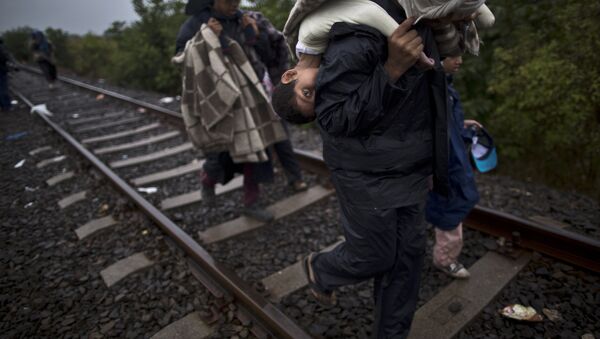 Migrantes sírios andando nos trilhos com crianças nas costas - Sputnik Brasil
