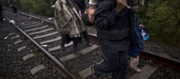 Migrantes sírios andando nos trilhos com crianças nas costas - Sputnik Brasil
