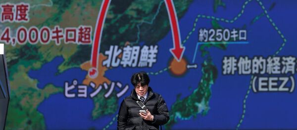 Um jovem passa na frente de uma televisão de rua em Tóquio, Japão, em 29 de novembro de 2017, durante uma transmissão da notícia sobre o lançamento de míssil pela Coreia do Norte - Sputnik Brasil